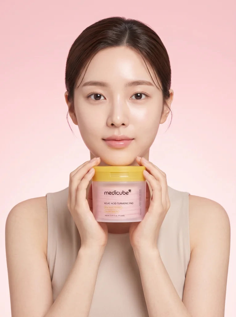 Medicube Kojic Acid Turmeric Pad. Modelo aplicando un pad despigmentante en su rostro para mejorar la luminosidad.