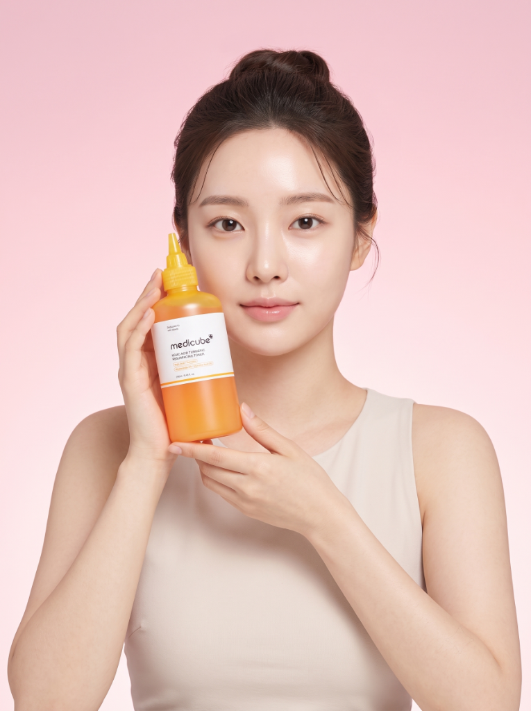 Modelo sosteniendo el tónico exfoliante Medicube Kojic Acid Turmeric con Ácido Kójico y Cúrcuma