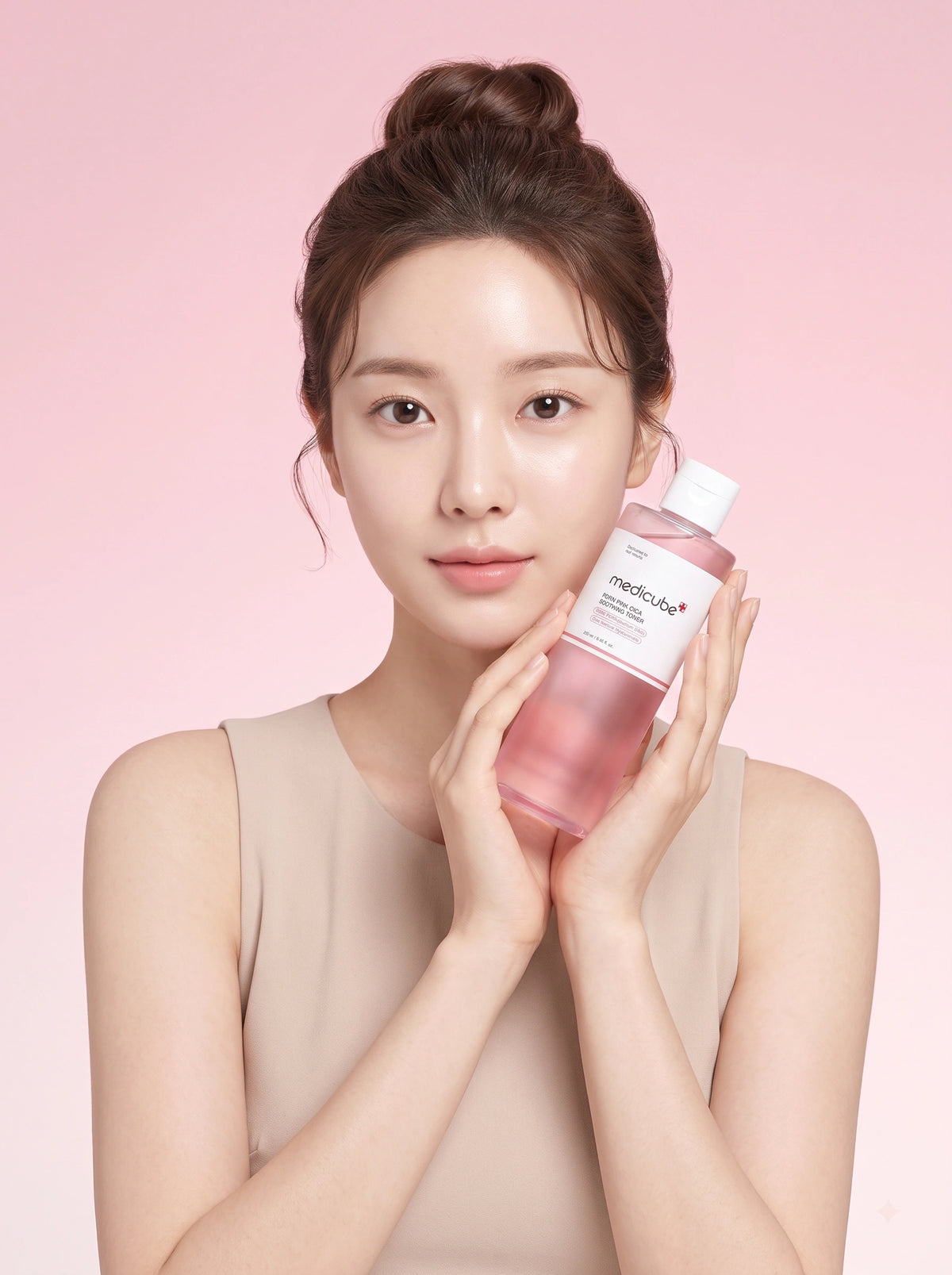 Medicube PDRN Pink Cica Soothing Toner. Modelo sosteniendo el frasco del tónico para piel sensible en la mano.