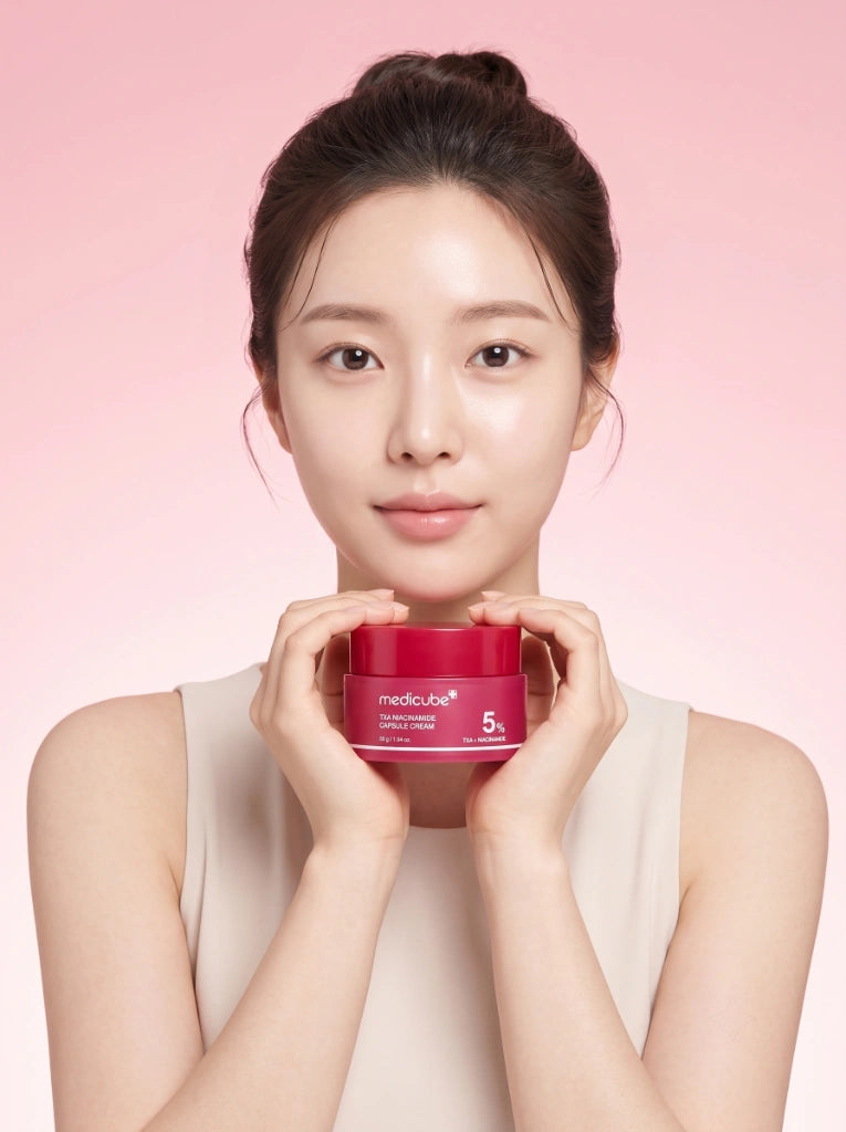 Medicube TXA Niacinamide Capsule Cream. Modelo sosteniendo el frasco de la crema para manchas en la mano.